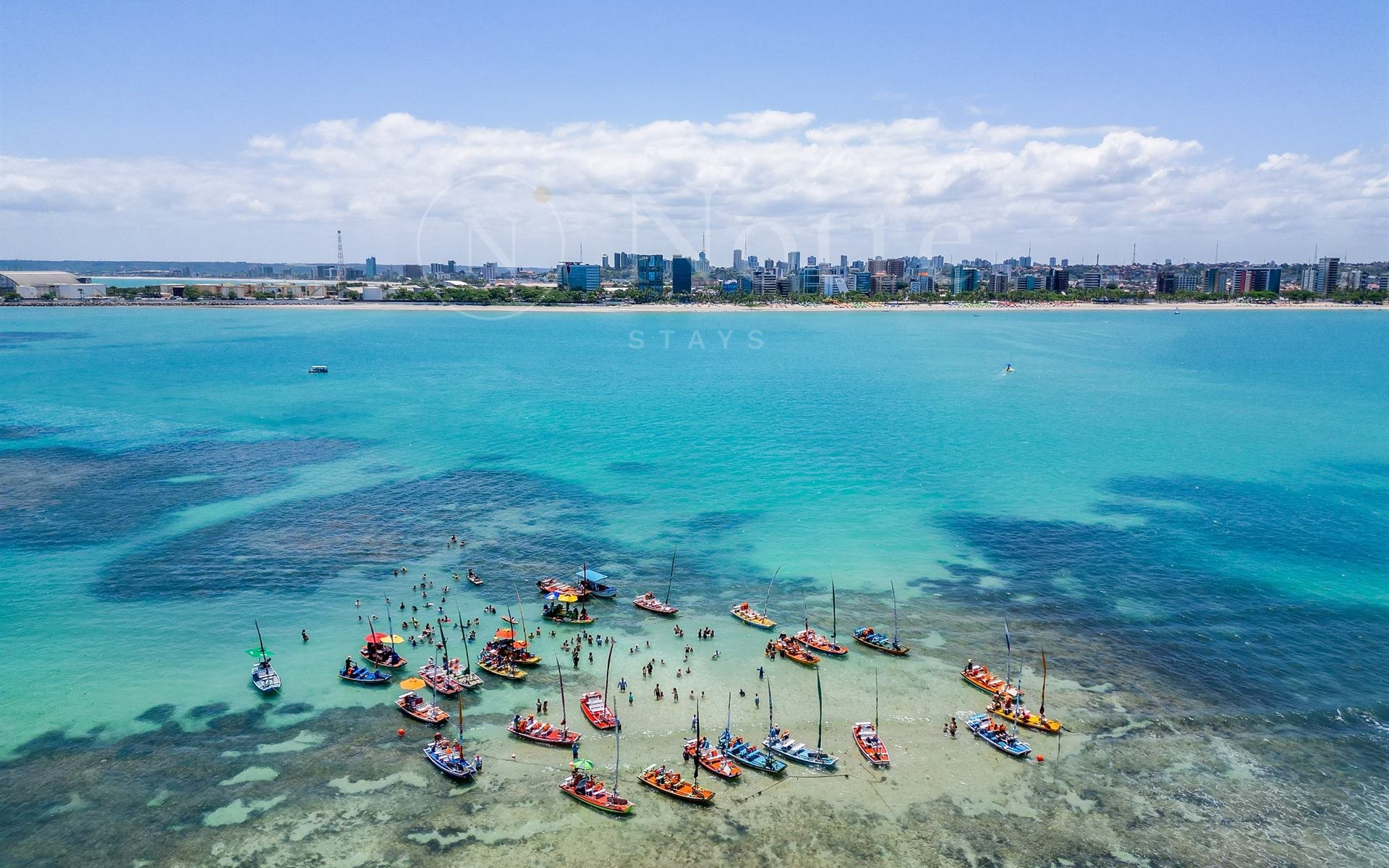 Piscinas naturais da Pajuçara vistas do alto, com jangadas sobre o mar verde-azulado